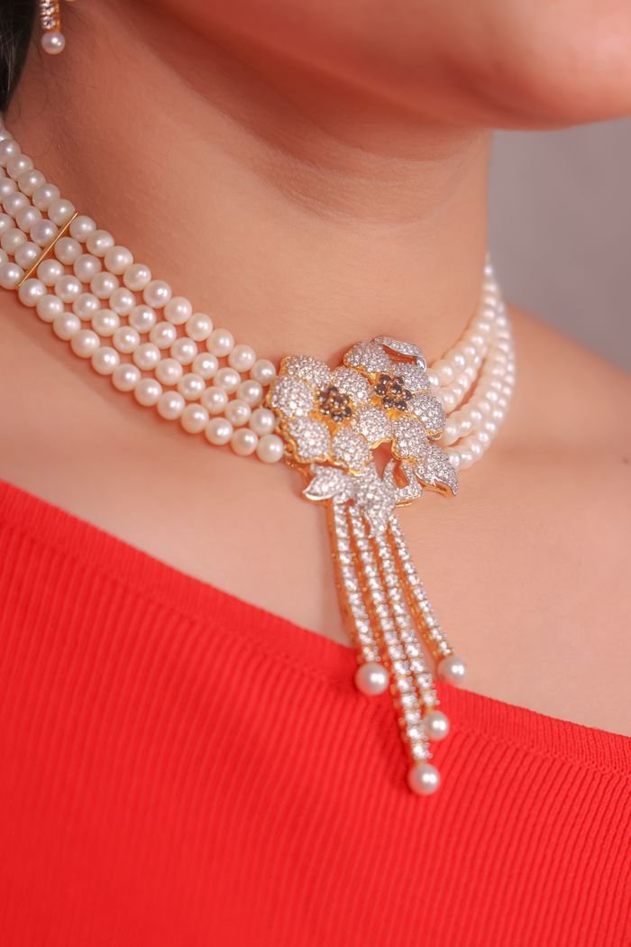 Close-up of a stunning pearl and diamond necklace on a model wearing red.
