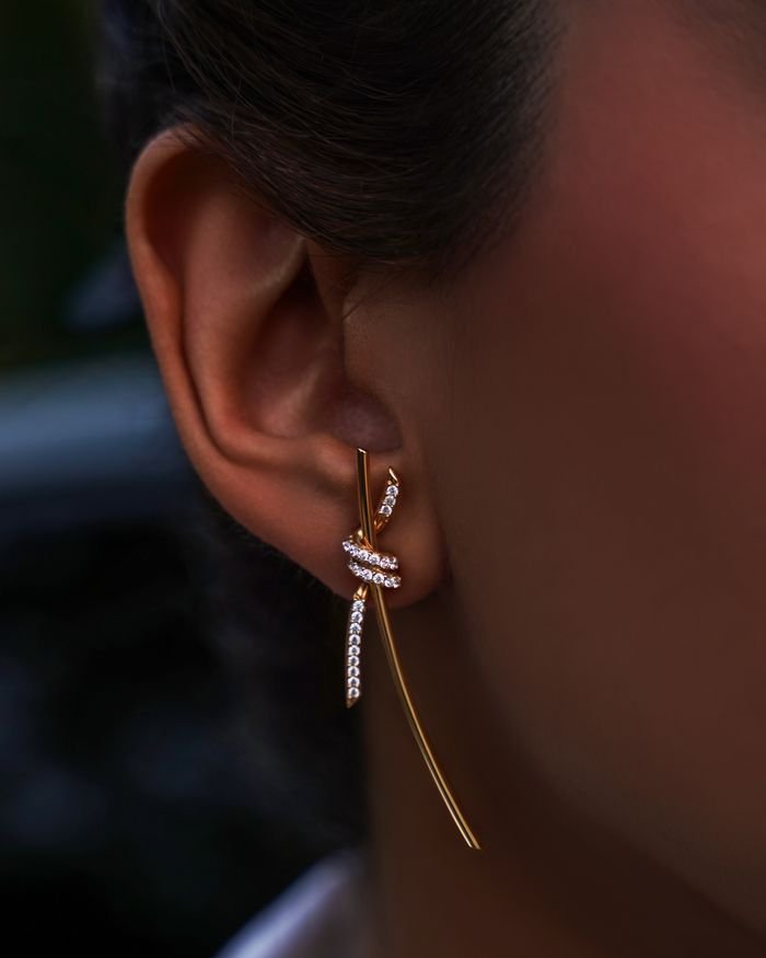 Close-up of a sophisticated gold earring adorned with diamonds on an adult woman's ear.