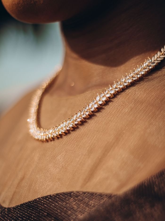 Close-up of an elegant diamond necklace on a female model's neck, showcasing luxury jewelry in soft lighting.
