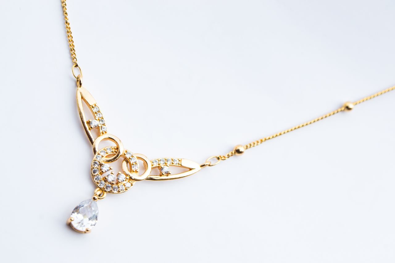 Luxury gold necklace featuring diamond accents on a white background.